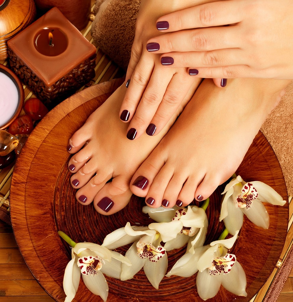 Basic pedicure with dark polish, candle, and orchids at Mina Nails